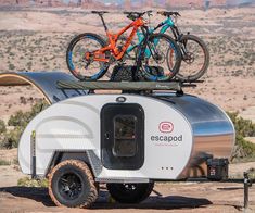 two bikes are mounted on the roof of an airscoop trailer in the desert