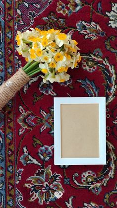 the flowers are sitting on top of the rug next to the photo frame and cork