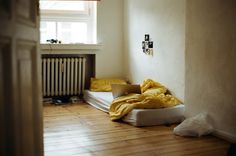 an unmade bed sitting in front of a window next to a radiator