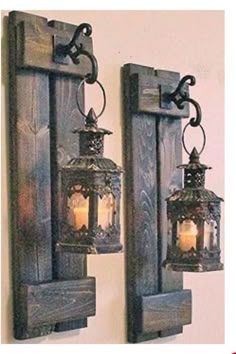 two lanterns are hanging on the wall next to each other with candles in them as if they were made out of wood