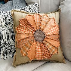 an orange and black decorative pillow sitting on top of a white couch next to pillows