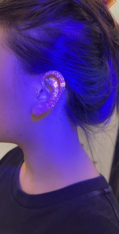 a woman with blue hair wearing an earring in the shape of a donut