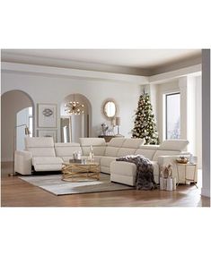 a living room with white furniture and a christmas tree in the corner on the wall