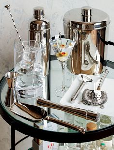 a table topped with glasses and silverware on top of a glass table covered in bottles