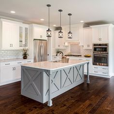 a kitchen with white cabinets and an island in the middle, surrounded by wood flooring