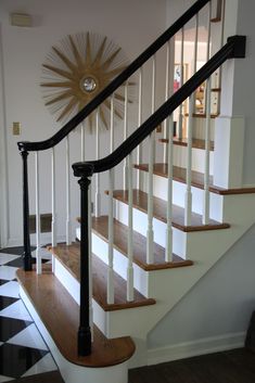 a staircase with black and white checkered flooring next to a clock on the wall