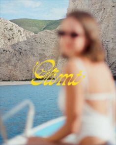 a woman sitting on top of a boat in the ocean next to a rocky cliff