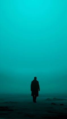 a man walking on the beach at night with his back turned to the camera,