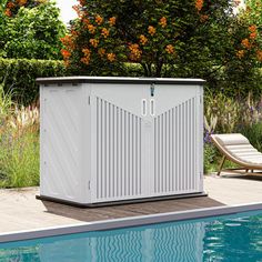 a white storage box sitting next to a swimming pool in a garden with orange flowers