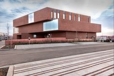 an empty parking lot in front of a red brick building with lots of windows on it