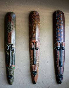 three african masks are hanging on the wall