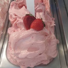 two strawberries on top of a pink frosted cake