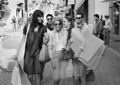 three women walking down the street with shopping bags