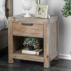 a small wooden table with a potted plant next to it on top of a bed