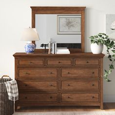 a dresser with a mirror and vase on top of it next to a lamp in a room