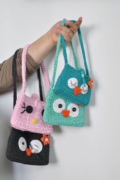 two crocheted purses are hanging on the wall, one with an owl and cat design