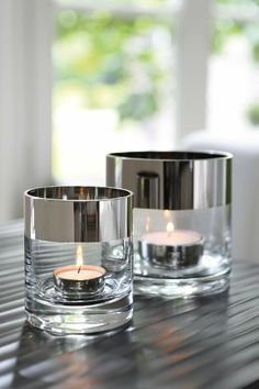 two glass candles are sitting on a table