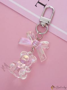 a clear key chain with a pink teddy bear on it's side and a name tag attached to it