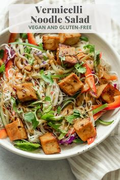 a white bowl filled with salad and tofu on top of a striped towel next to a fork