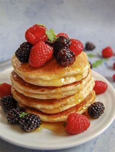 a stack of pancakes topped with berries and syrup