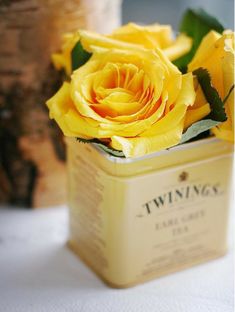 two yellow roses in a tin on a table