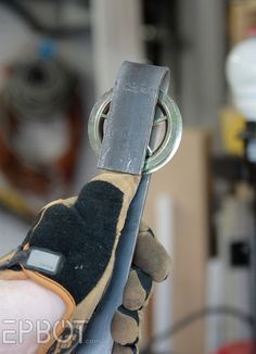 a hand holding a pair of scissors in it's right hand with other tools nearby