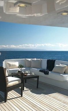 a couch sitting on top of a wooden deck next to the ocean