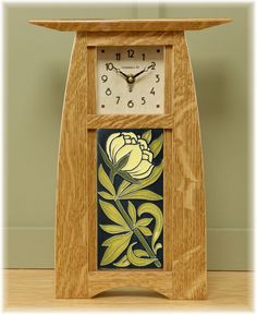 a small wooden clock with flowers painted on the front and sides, sitting on a table