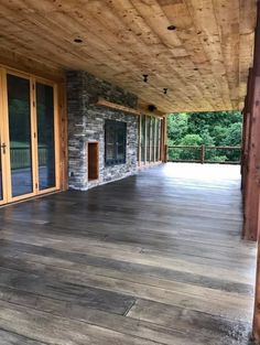 an empty covered porch with sliding glass doors and stone fireplace in the center, surrounded by wood paneling