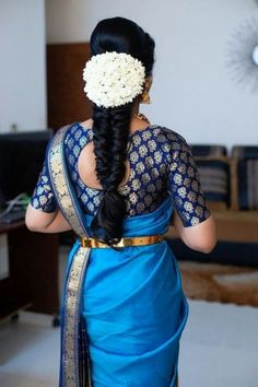 a woman wearing a blue sari with flowers in her hair, looking down at the floor