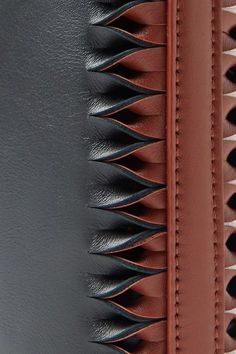 the back side of a black and brown purse with spikes on it's sides