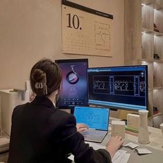 a woman sitting in front of two computer monitors