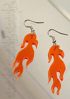 the earrings are made out of plastic and have an orange fish design on each side