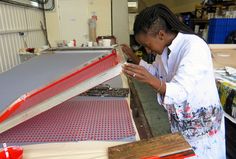 a woman working on a piece of furniture in a factory or workshop with tools and materials