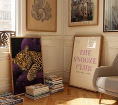 there is a chair and some books on the floor in front of a wall with pictures