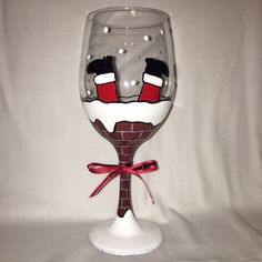 a wine glass decorated with santa's stockings and boots on the bottom is sitting on a white surface