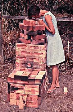 a woman leaning over a pile of wooden blocks