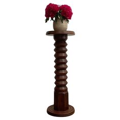 a vase with flowers sitting on top of a wooden stand