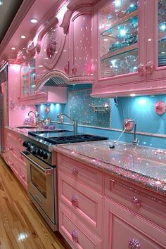 a kitchen with pink cabinets and shiny counter tops, along with an oven and stove top