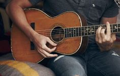 a man sitting on a couch playing an acoustic guitar