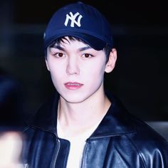 a young man wearing a new york yankees hat and black leather jacket is looking at the camera