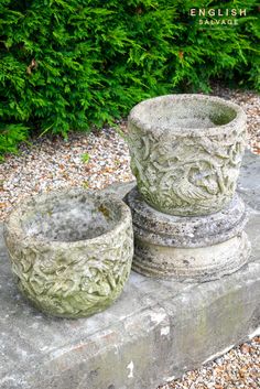 two cement pots sitting on top of a stone slab