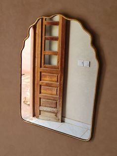 a mirror that is on the wall with a wooden door in it's reflection