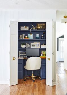 an open door leading into a home office with blue bookshelves and white chairs