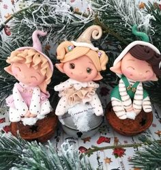 three little figurines sitting on top of a christmas ornament next to a tree