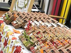 many small boxes are sitting on a table with orange and green ribbons tied to them