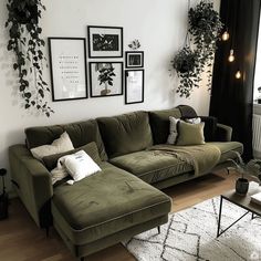 a living room with green couches and pictures on the wall above them, along with potted plants