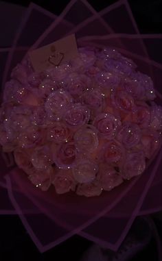 a bouquet of pink roses with water droplets on it and a card attached to the top