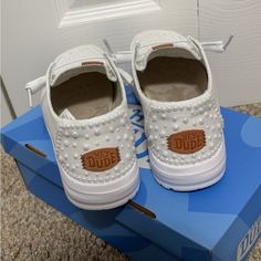 a pair of white shoes sitting on top of a blue box