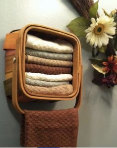 towels are stacked in a basket on the wall